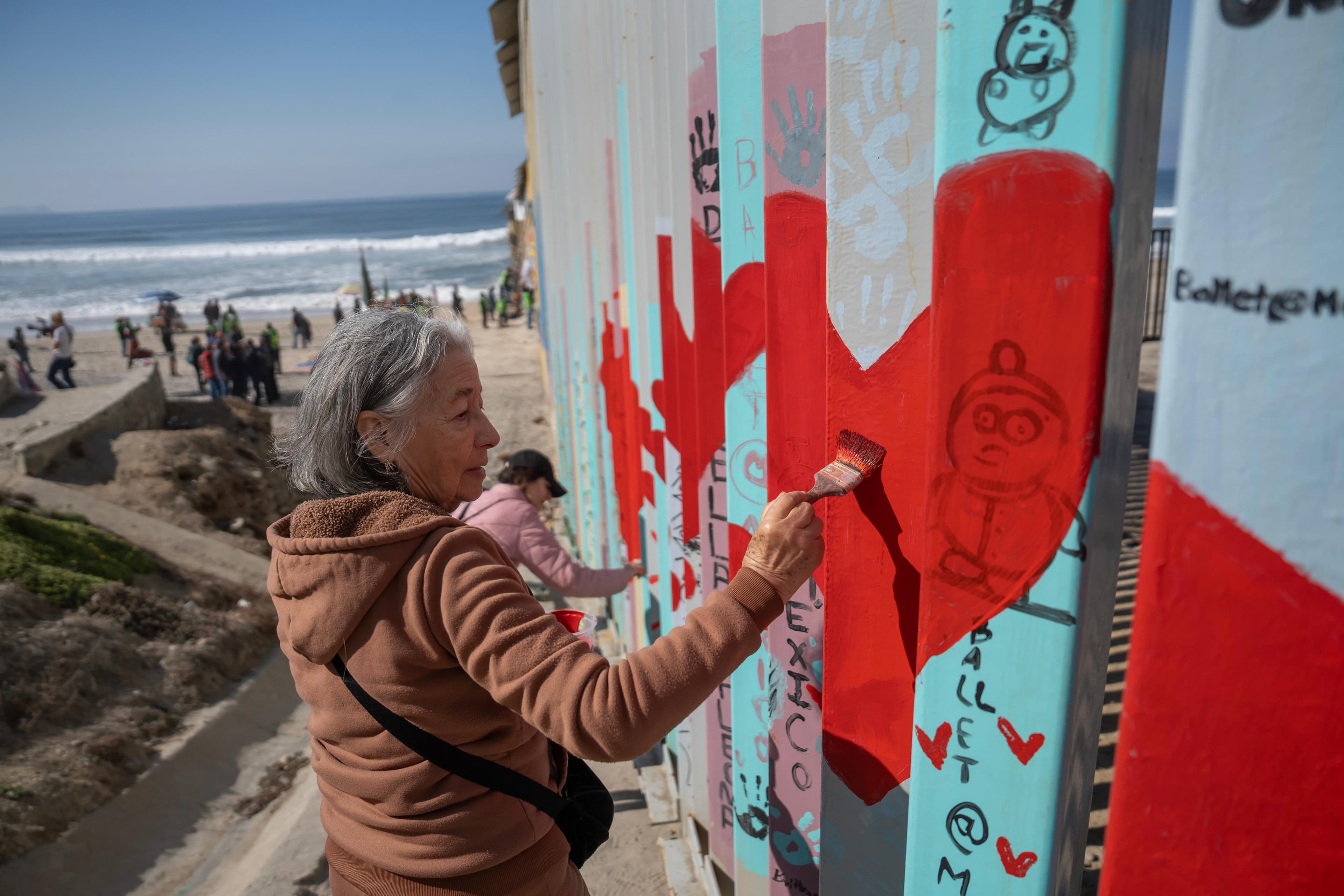 El artista Enrique Chiu lidera la jornada de pintura en el Mural de la Hermandad, un símbolo de esperanza y solidaridad para los migrantes.