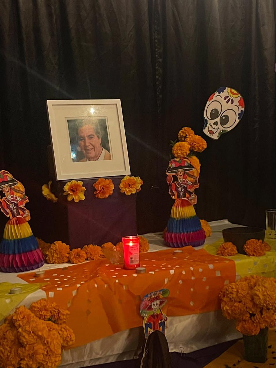 Flores, catrinas y una vela que adornan el altar